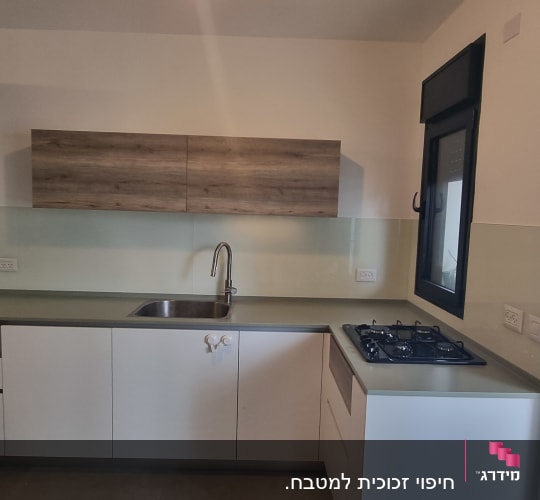 מטבח עם חיפוי זכוכית מעל השיש והכיור